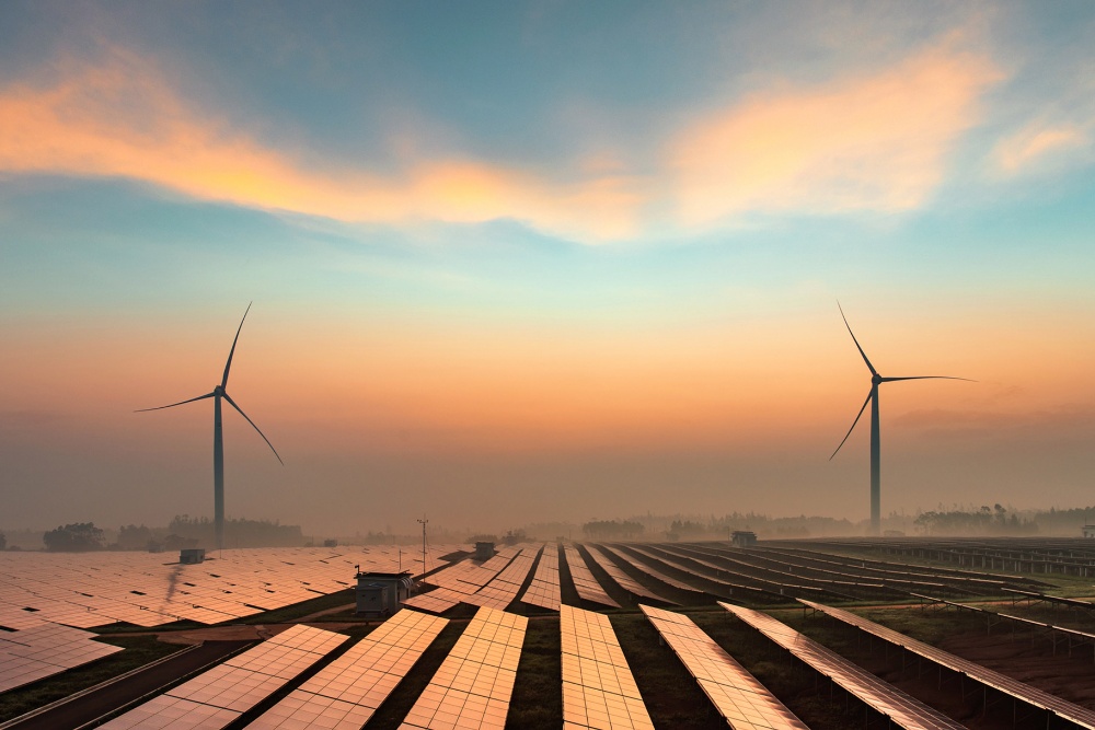 Megújuló energiaforrások – köztük szélturbinák és napelemek – naplementekor.
