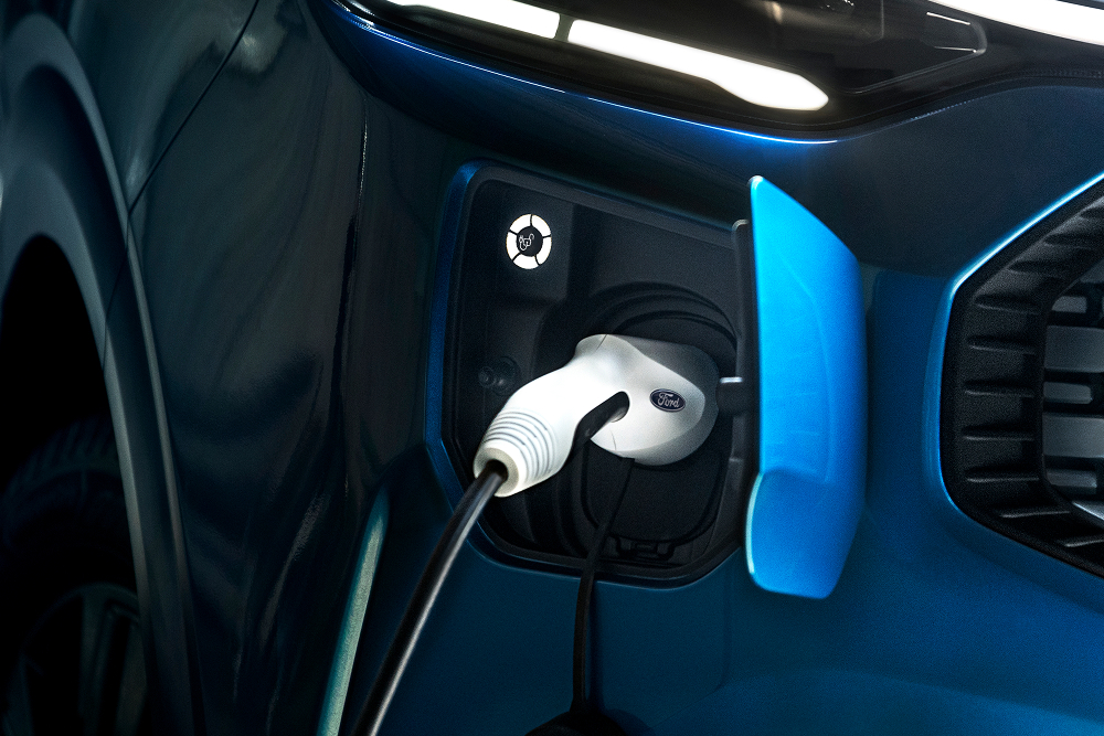 Közelképen látunk egy Ford E-Transit Custom elektromos furgonhoz csatlakoztatott elektromos töltőkábelt.