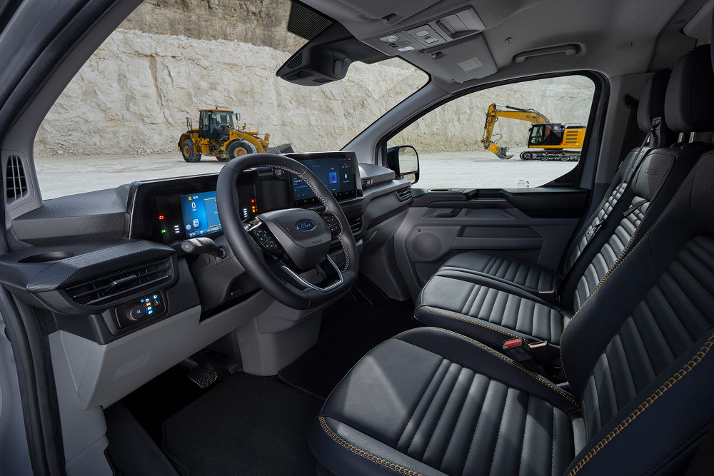Egy kőbányában parkoló Ford E-Transit Custom elektromos furgon utasterében az üléseket és a kormánykereket látjuk.