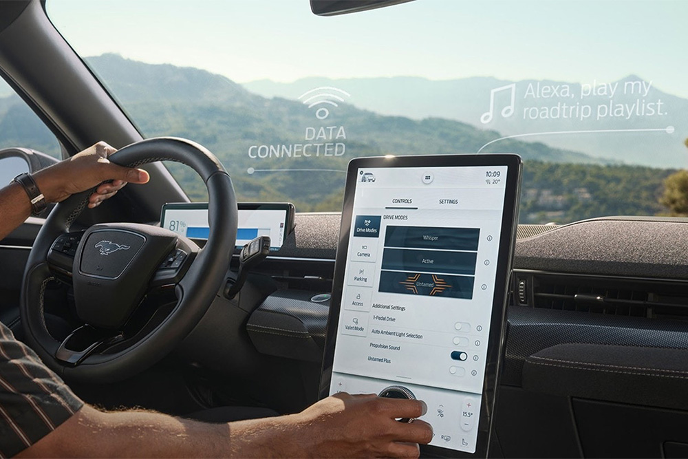 Közelképen egy Ford Mustang Mach-E-t vezető személy, aki a 15,5''-os SYNC 4 érintőképernyőt használja.