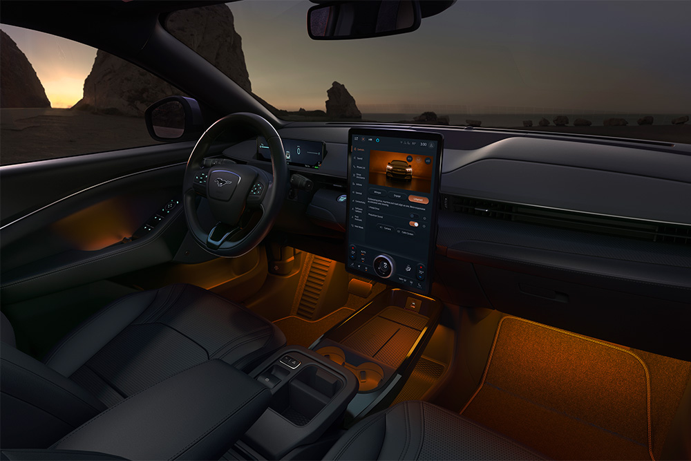 A Ford Mustang Mach-E utastere éjjel. A 15.5" os SYNC 4 érintőképernyő és a LED-izzós hangulatvilágítás narancsszínű.
