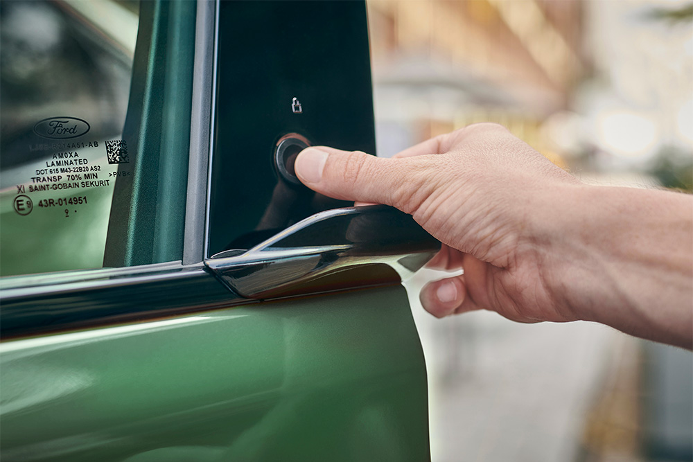 Közelképen egy kéz, mely egy zöld Ford Mustang Mach-E ajtógombjának megnyomásával aktiválja az E-Latch rendszert.