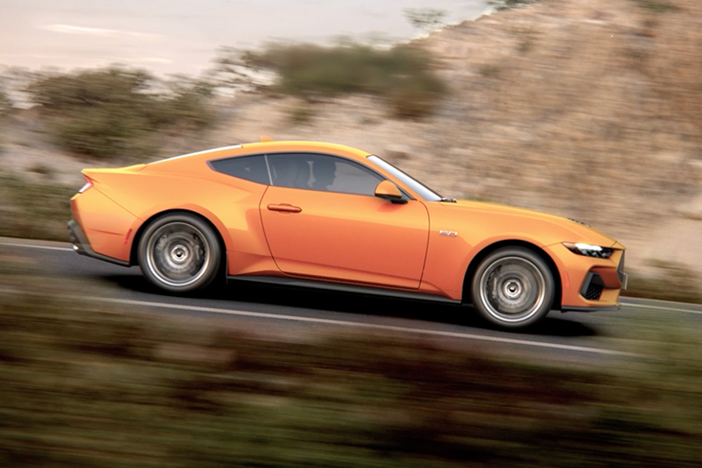 Oldalnézet a Ford Mustang GT Fastback oldalnézetből. Úton haladó Fastback Orange Fury fényezéssel.