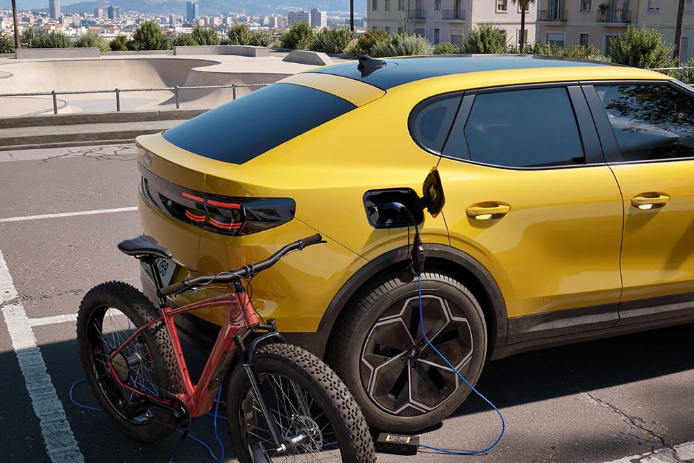 Sárga Ford Capri® városi környezetben parkol, s közben egy piros elektromos kerékpárt tölt.