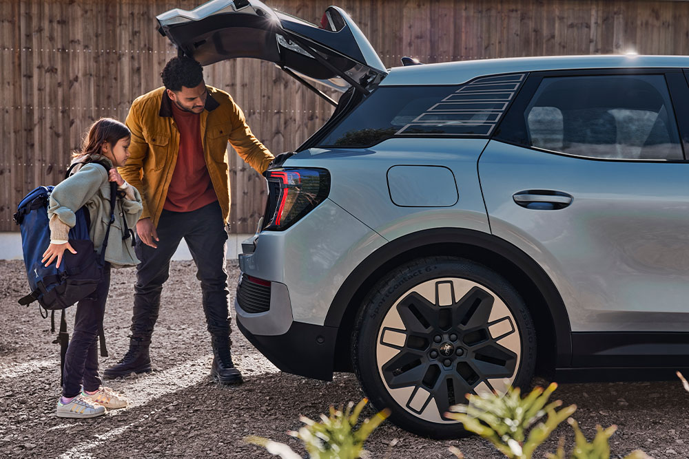 Egy apa és lánya ezüstszínű Ford Explorer® csomagtartójába pakolnak.