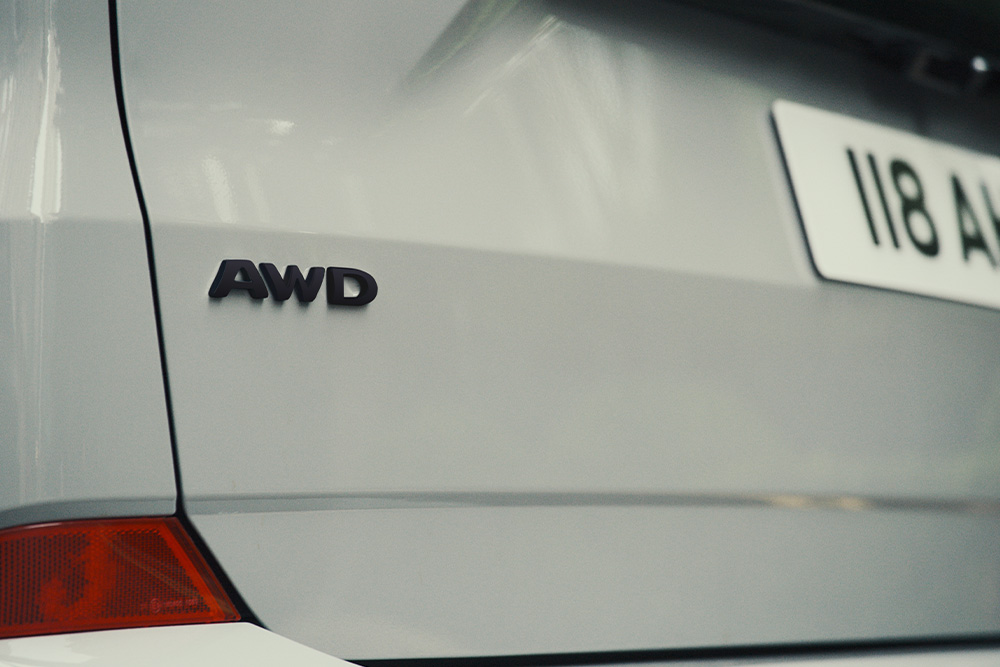 Egy ezüstszínű Ford Tourneo Custom hátulja az „AWD” feliratra fókuszálva.