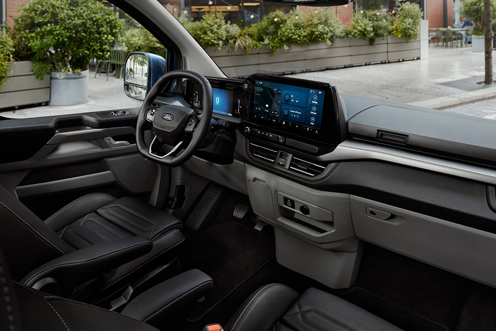 A Ford Tourneo Custom belülről, a vezetőülést, a műszerfalat és a központi konzolt mutatva.
