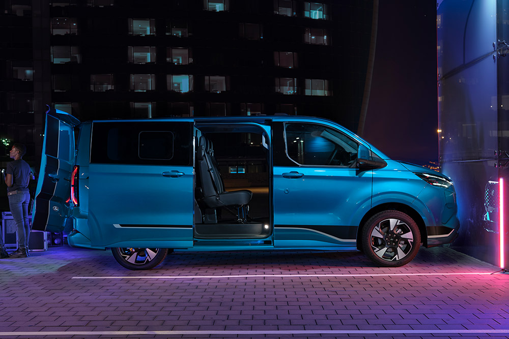 Egy kék Ford E-Transit Custom dupla kabinos elektromos személyszállító nyitott ajtókkal.