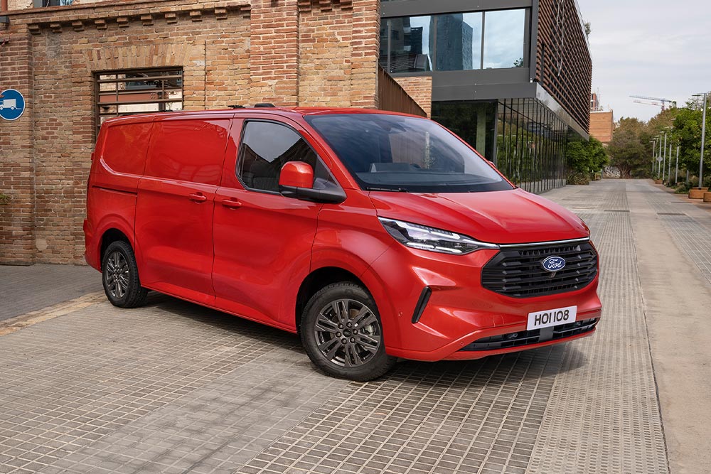 Egy piros Ford Transit Custom egy utcán parkol a városban.