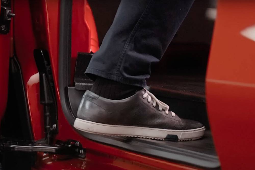Foot stepping into a red Ford E-Transit Custom electric van.
