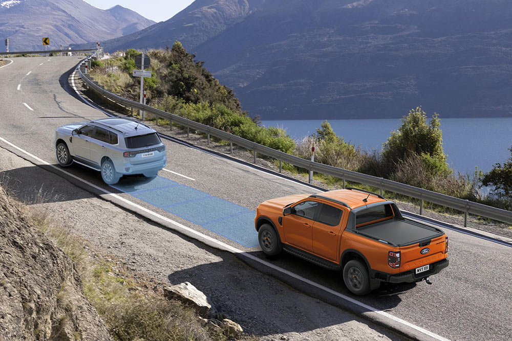 Sárga Ford Ranger Raptor halad egy festői hegyvidéki úton, a jármű vezetéstámogató rendszereit bemutatva.