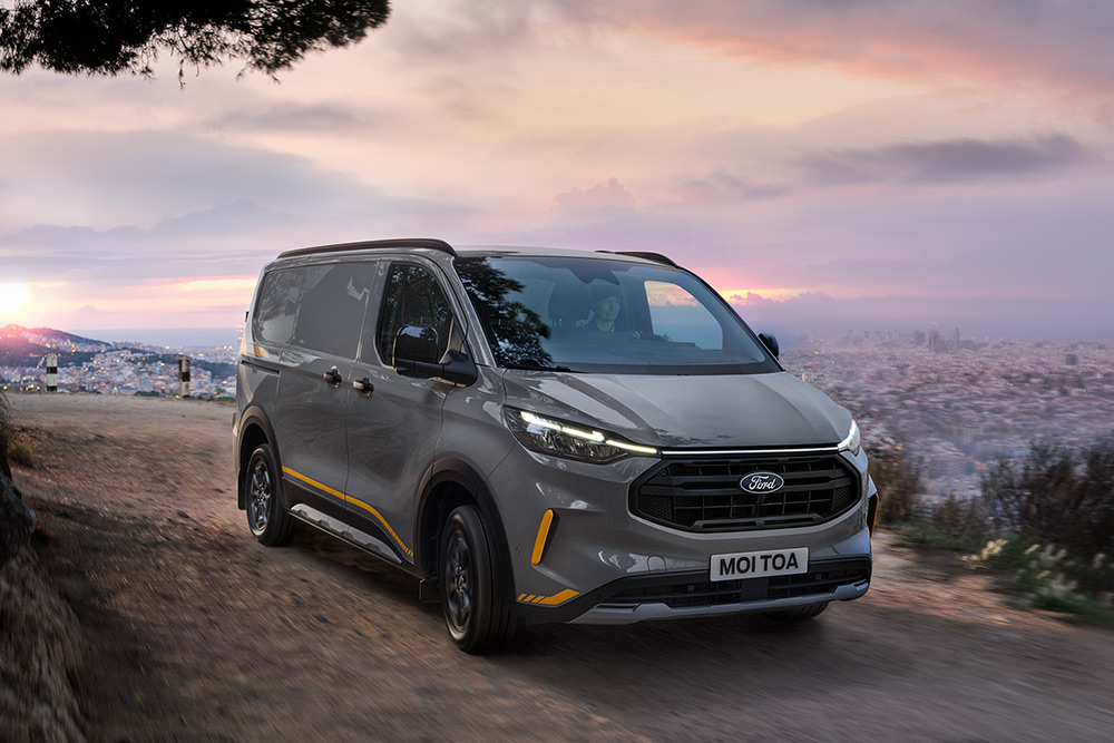 Szürke Ford Transit Custom Trail sárga dekorcsíkokkal.
