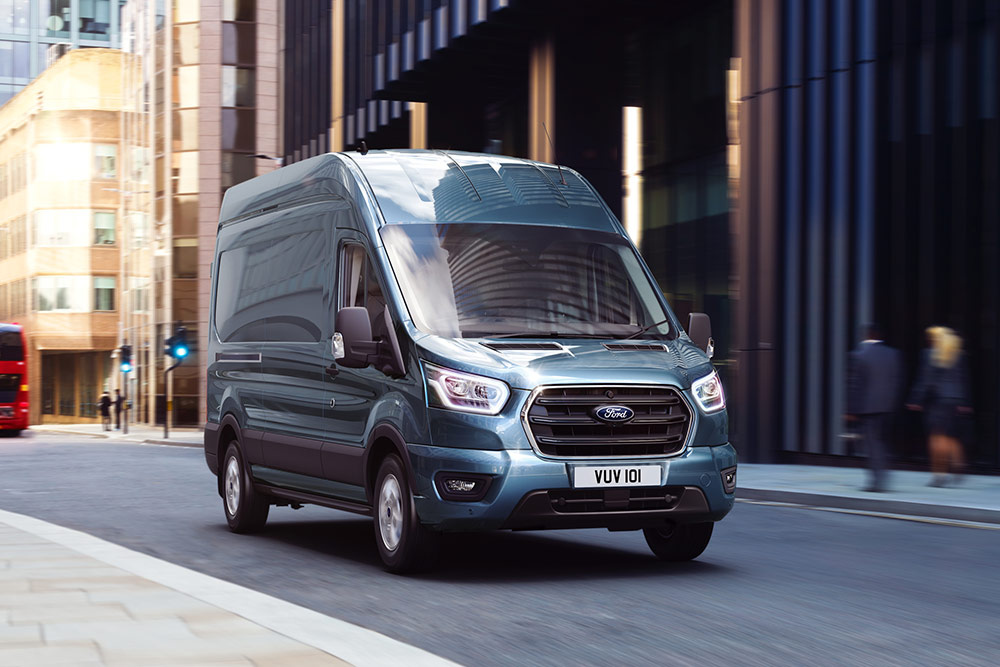 Egy Ford Transit Van egy városban halad az úton.