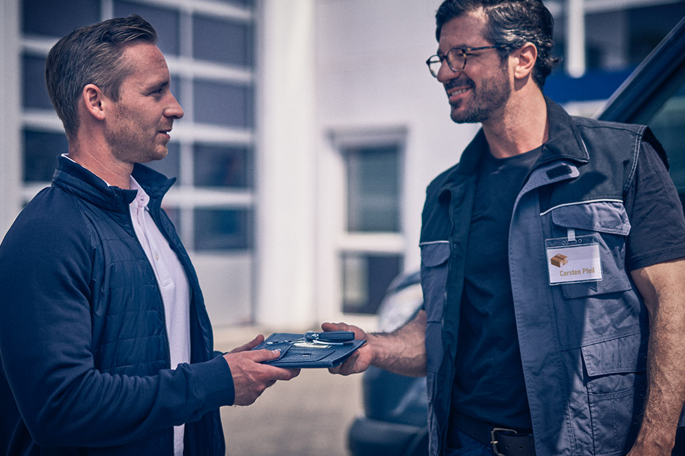 Egy férfi egy tabletet ad át egy másik férfinak egy Ford Transit áruszállító előtt.
