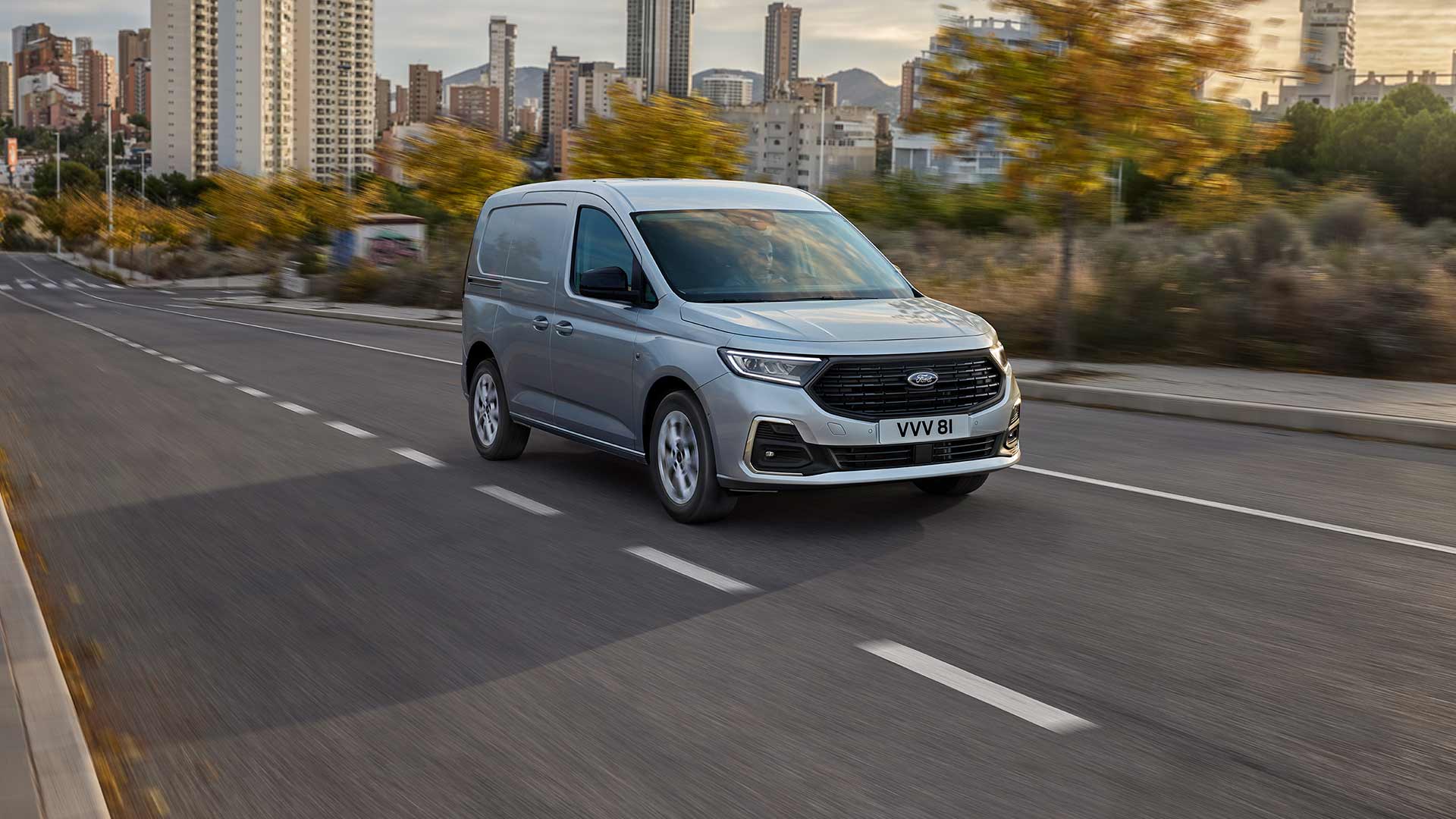 A Ford Transit Connect városban halad, krómozott külső ködlámpáit és automatikus fényszóróit látjuk közelről.