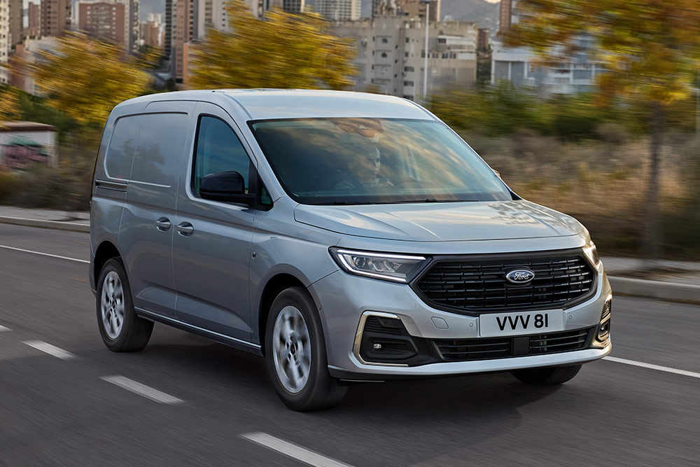 A Ford Transit Connect városban halad, krómozott külső ködlámpáit és automatikus fényszóróit látjuk közelről.