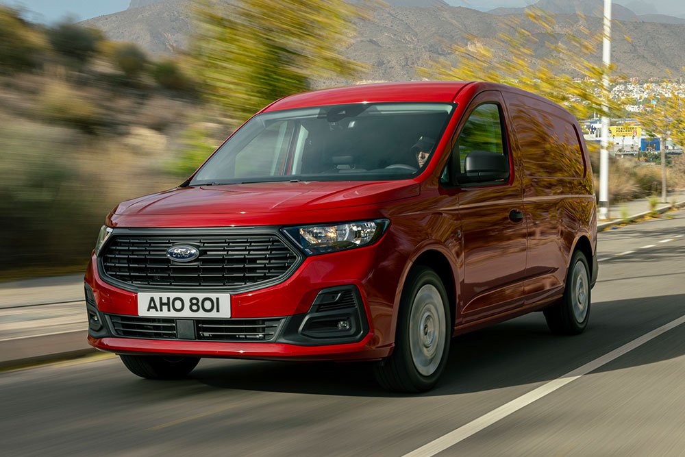 A Ford Transit Connect Trend egy úton halad, a kép az első hűtőrácsra és az automatikus fényszórókra közelít rá.