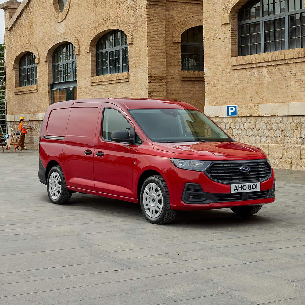 Ford Transit Connect Trend Lava Red színben, melynek első hűtőrácsát és automatikus fényszóróit látjuk közelről.