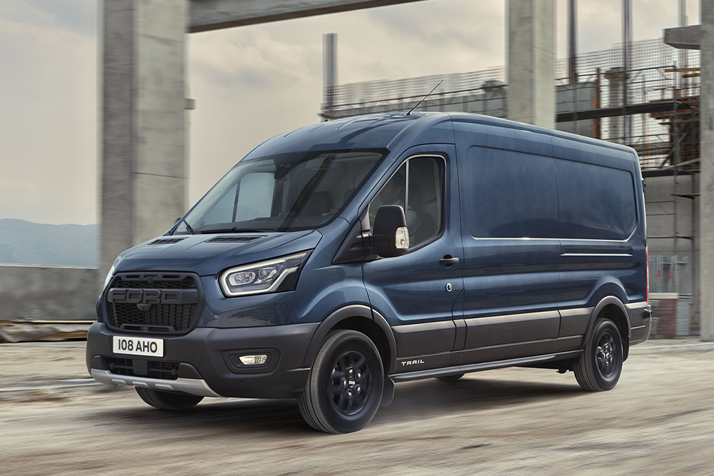 Egy Ford Transit Van opcionális Trail csomaggal, amint egy ipari parkban halad.