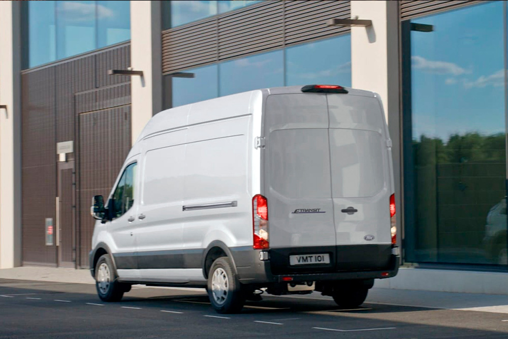 Egy ezüstszínű Ford Transit Van hátulja, amint egy városi utcán parkol.