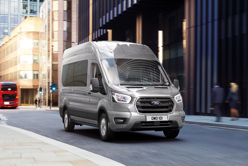 Egy Ford Transit Van egy városban halad az úton.