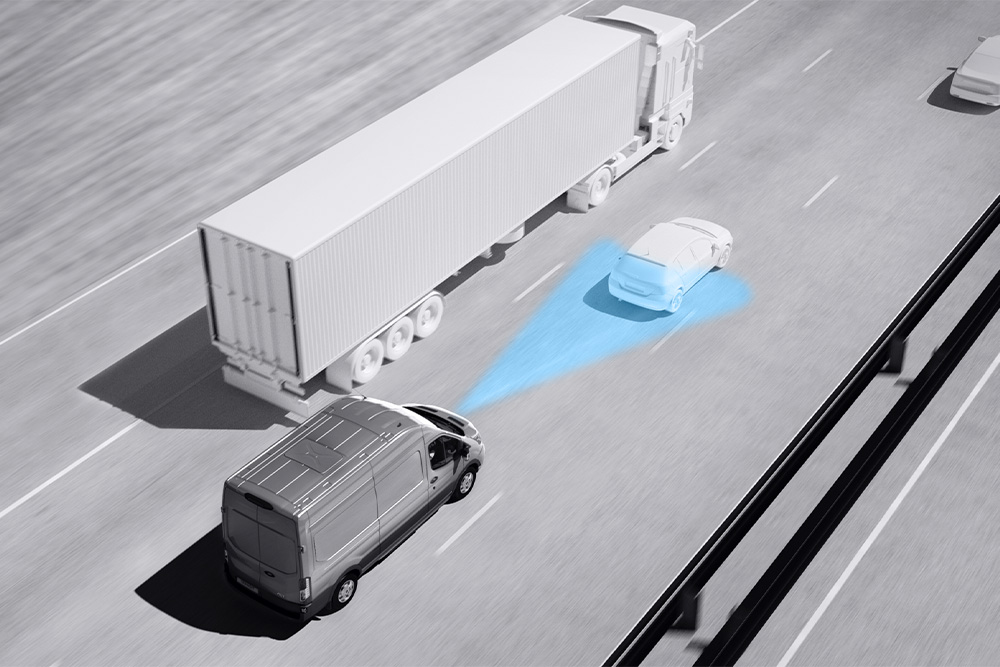 A Ford Transit Van szürkeárnyalatos rajza kék vonalakkal az úton, amely a fejlett vezetéstámogató rendszerek használatát szemlélteti.