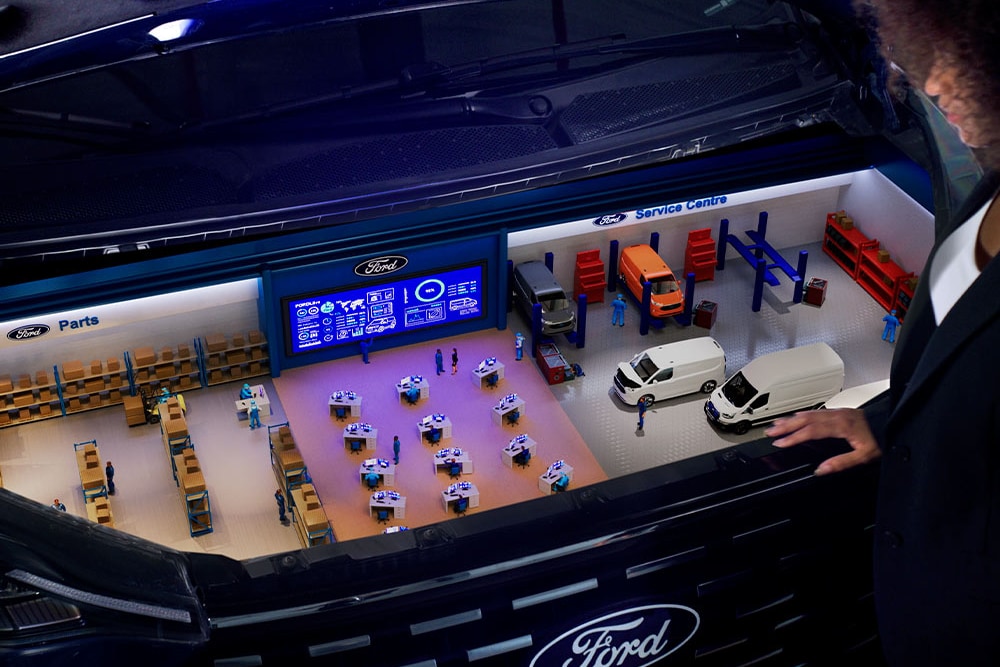 O ilustrație grafică arată un centru de service și un depozit de piese Ford sub capota deschisă a unui vehicul negru.